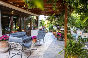 un patio con sillas, mesas y plantas en The Village House, en Volos