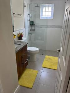 W łazience znajduje się prysznic, toaleta i żółte maty. w obiekcie Spacious apartments Crystal Waters w mieście Lucea