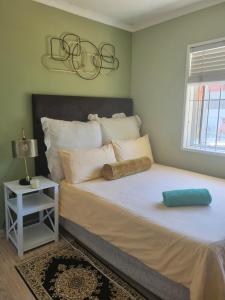 a bedroom with a large white bed with a night stand at 76 on d'Urban Street, Bothasig in Cape Town
