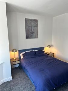 a bedroom with a blue bed and two lamps at Arlos in Blackpool