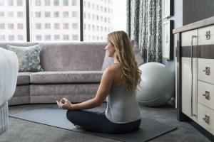 a woman sitting in a yoga pose in a living room at The Ritz-Carlton Atlanta in Atlanta