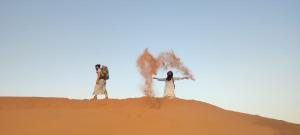 três pessoas em pé em cima de uma duna de areia em Bivouac Beauté de Désert em Mhamid