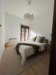 a white bedroom with a large bed and a chandelier at Mountain View Apartment in Mieres