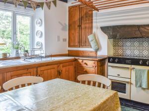 a kitchen with wooden cabinets and a table with chairs at Ty Dyfnant Cottage in Penmachno