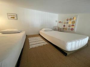 two twin beds in a room with a rug at NOIRMOUTIER - Petite maison 500m plage Sableaux in Noirmoutier-en-l'lle