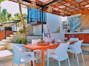 an outdoor dining room with a wooden table and white chairs at Las Terrazas de Barili in Barili