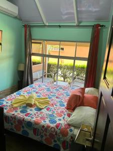 a bedroom with a bed with a colorful comforter and a window at Villas Paraíso Jacó B20 in Jacó