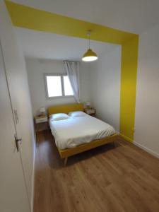 a bedroom with a bed and a yellow wall at Appartement Le Secret, Proche Sanctuaires in Lourdes