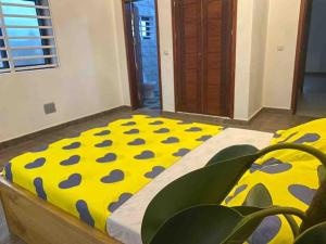 1 dormitorio con 1 cama con lunares amarillos y azules en Appartement climatisé et cozy., en Abomey-Calavi