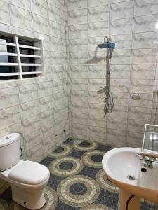 y baño con aseo y lavamanos. en Appartement climatisé et cozy., en Abomey-Calavi