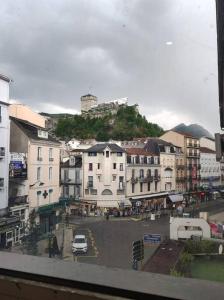 a city street with buildings and a hill in the background at Appartement Le Secret, Proche Sanctuaires in Lourdes