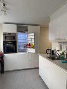 cocina con armarios blancos y nevera abierta en Lovely apartment with parking in the heart of city, en Lillehammer