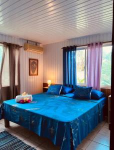 1 dormitorio con 1 cama azul con sábanas y ventanas azules en Fare ManuVai, en Haapu