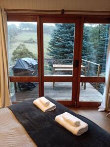 a bedroom with a bed with two towels on it at The 'Nook' - Cabin in the Tassie Wilderness! in Ridgeway