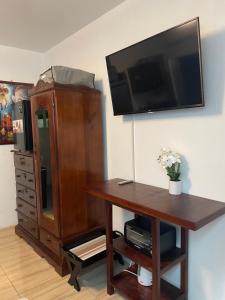 a living room with a tv and a wooden desk at Centrally Located Room - 5 in Port Antonio