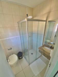 a bathroom with a shower and a toilet and a sink at Hotel Enseada in São Francisco do Sul