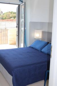 1 dormitorio con cama azul y balcón en Sikelia en Marina di Ragusa