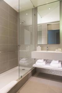 y baño con ducha, lavabo y espejo. en Courtyard by Marriott Santiago Las Condes, en Santiago