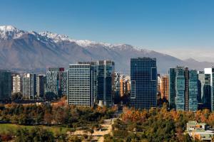 a city with skyscrapers in front of snowy mountains at Courtyard by Marriott Santiago Las Condes in Santiago