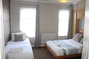 a bedroom with two beds and a window at Grays Rest Over, with free parking in Grays Thurrock