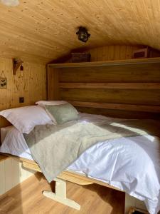 a bed in a room with a wooden wall at The Stone Wall Hideaway in Portglenone