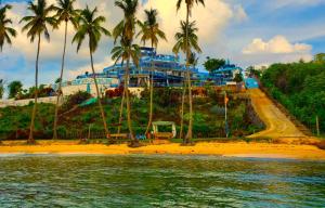 a building on a beach with palm trees and the water at Sunset Samana in Las Galeras
