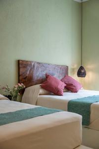 Cette chambre comprend 2 lits avec des oreillers roses. dans l'établissement Hotel Bindani’, à Santa Cruz Huatulco