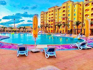 a swimming pool at a resort with chairs and buildings at قريه اكوا فيو - الساحل الشمالى - الكيلو91 in El Alamein