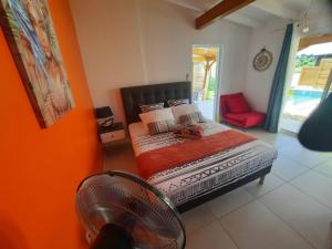 a bedroom with a bed and a red chair at bungalow hibis.kiss971 in Baie-Mahault