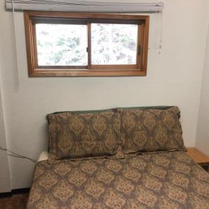 a bed with a pillow and a window above it at Porter’s Place in Vanderhoof