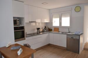a kitchen with white cabinets and a wooden table at La LLar de Julia in Tibi