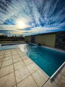a large swimming pool with the sun in the sky at DON FRANCISCO Cabañas Boutique in San Rafael