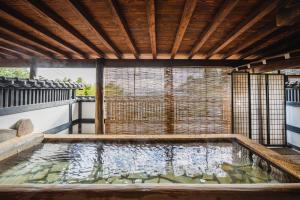 uma piscina de água num quintal com tecto de madeira em 伊豆Cocoグランピングリゾート em Ito