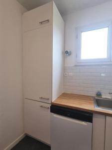 une cuisine blanche avec un évier et une fenêtre dans l'établissement So Cosy Home Paris-Sceaux/Bourg-la-Reine., à Sceaux