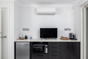 a kitchen with a counter with a tv and a microwave at Whale Studio Suite in Anna Bay