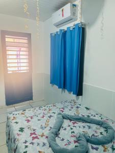 een slaapkamer met een bed met blauwe lakens en een raam bij La casita lilás in Beberibe