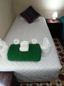 a bed with towels and a green blanket on it at HOSTAL LA PAZ in Antigua Guatemala