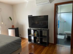 uma sala de estar com uma televisão de ecrã plano num centro de entretenimento em Suite residencial, Villa da Luz em Curitiba