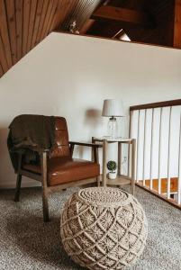 een woonkamer met een stoel en een poef bij Bluebird Cottage, walking distance to fairgrounds in Hutchinson