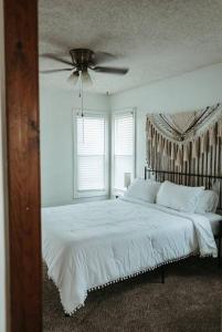 a bedroom with a white bed with a ceiling fan at Bluebird Cottage, walking distance to fairgrounds in Hutchinson
