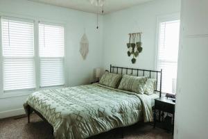 a bed in a bedroom with white walls and windows at Bluebird Cottage, walking distance to fairgrounds in Hutchinson