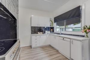 a white kitchen with white cabinets and a window at Bright and airy cosy cottage, close to town in Thirlmere