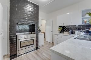 una cucina con muro di mattoni e forno di Bright and airy cosy cottage, close to town a Thirlmere