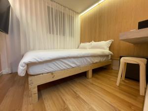 a bed in a small room with a wooden floor at SSH LK Hostel in Seoul