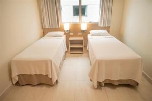 two beds in a hotel room with a window at Salinas Park Resort in Salinópolis +10 photos