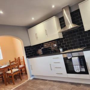 a kitchen with white cabinets and a table and a stove at Sunny South Shields House in Jarrow