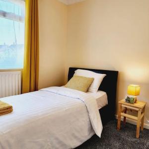 a bedroom with a bed and a table with a lamp at Sunny South Shields House in Jarrow