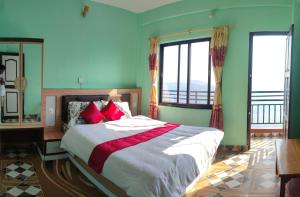 a bedroom with a large bed with green walls and windows at Sarangkot Hotel New Galaxy in Pokhara