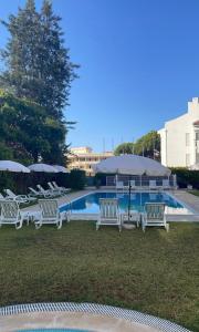a group of white chairs and umbrellas next to a pool at Algarve for you in Quarteira
