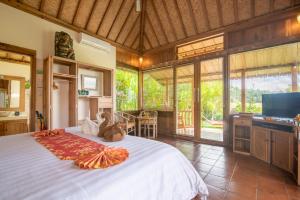 een slaapkamer met een groot bed en een televisie bij Bali Sawah Indah in Ubud